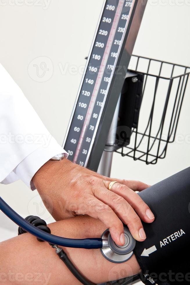 Doctor measuring blood pressure to a patient photo