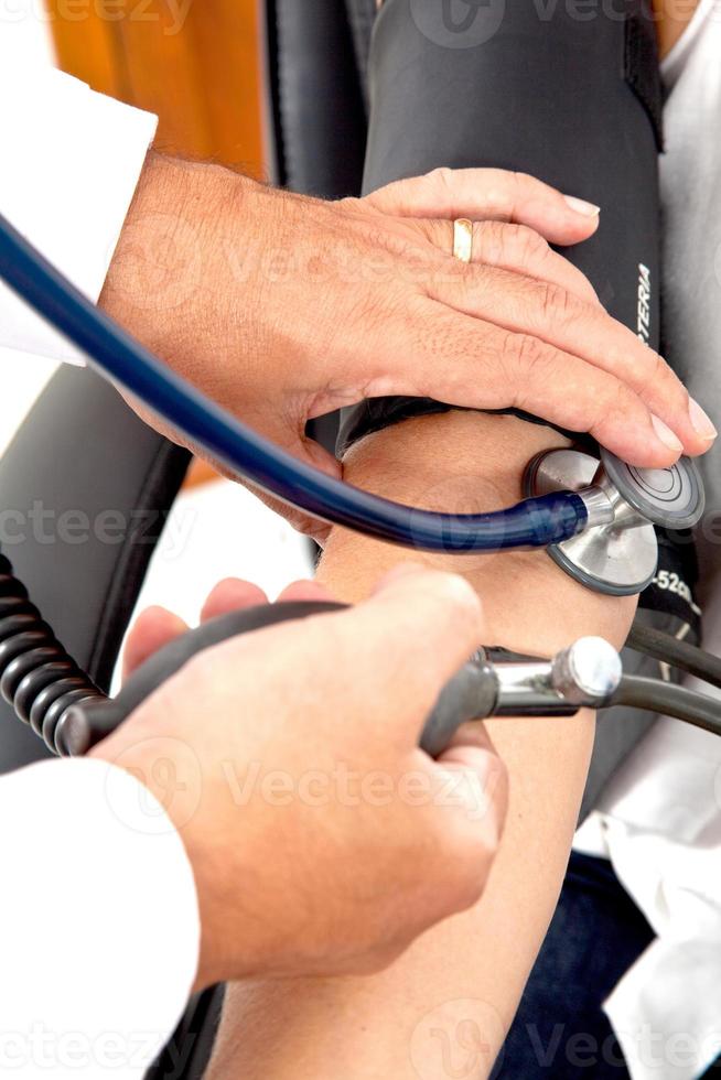 Doctor measuring blood pressure to a patient photo