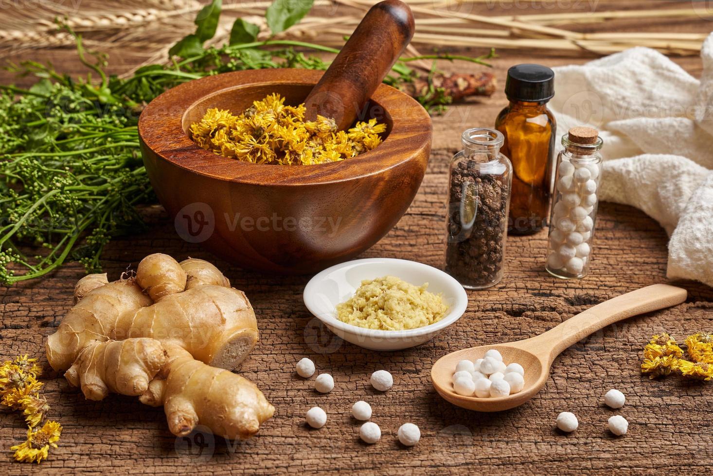 concept of homeopathic pills in a wooden spoon and bottles with the herb in a mortar with a pestle on wooden table background photo