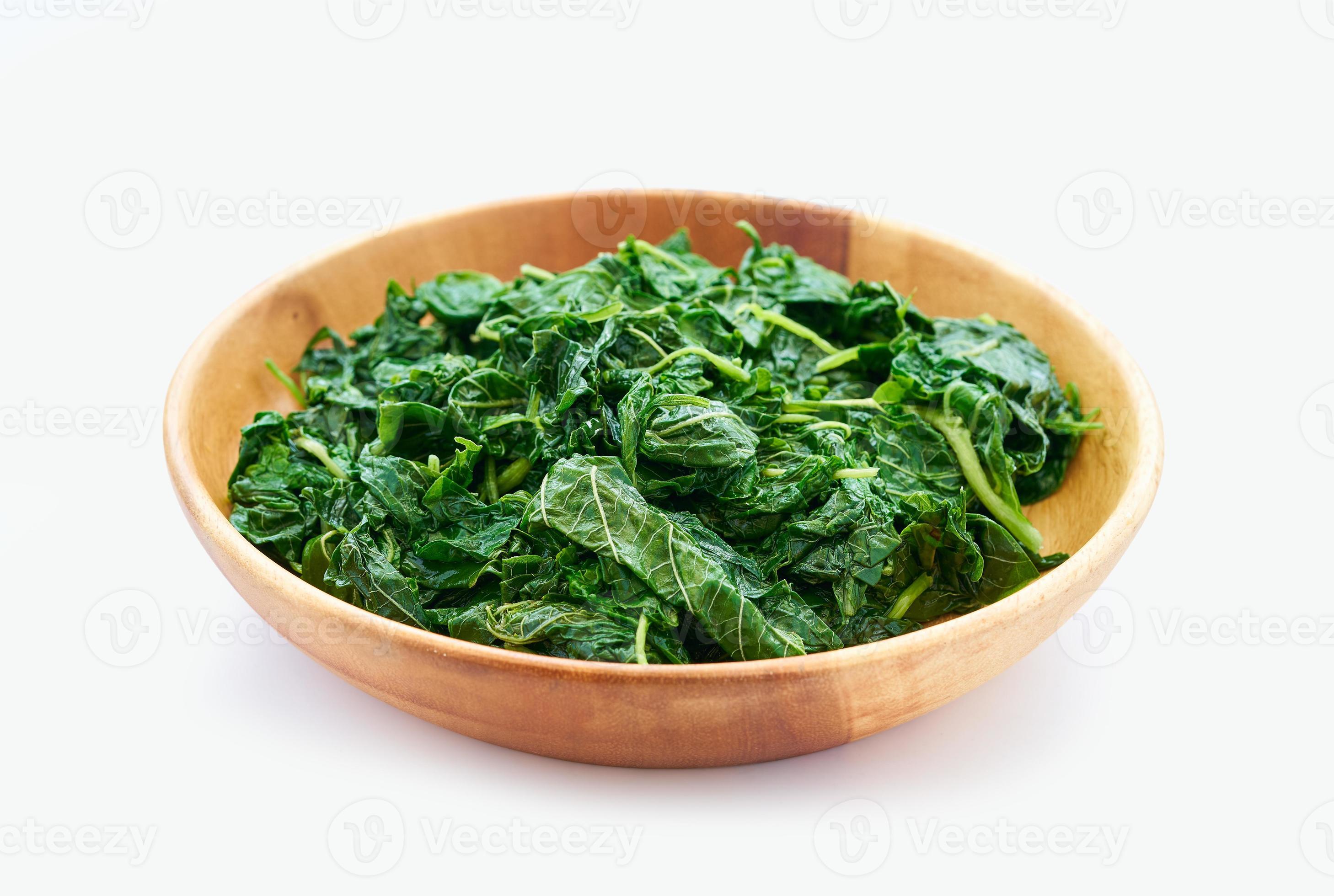 pile of green cook leaf spinach in wood bowl isolated on white