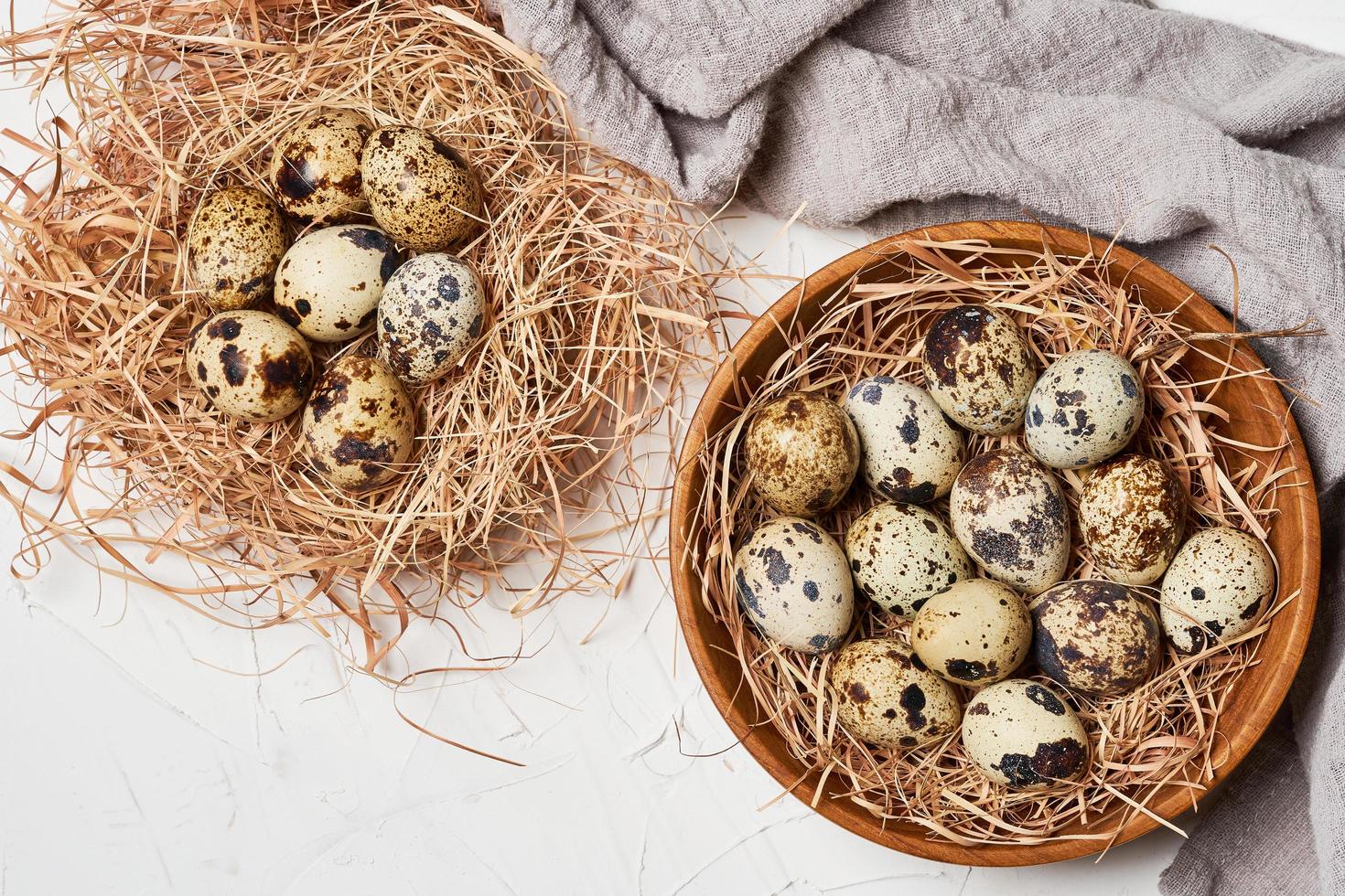 top view quail eggs in wooden bowl and nest on white table background photo