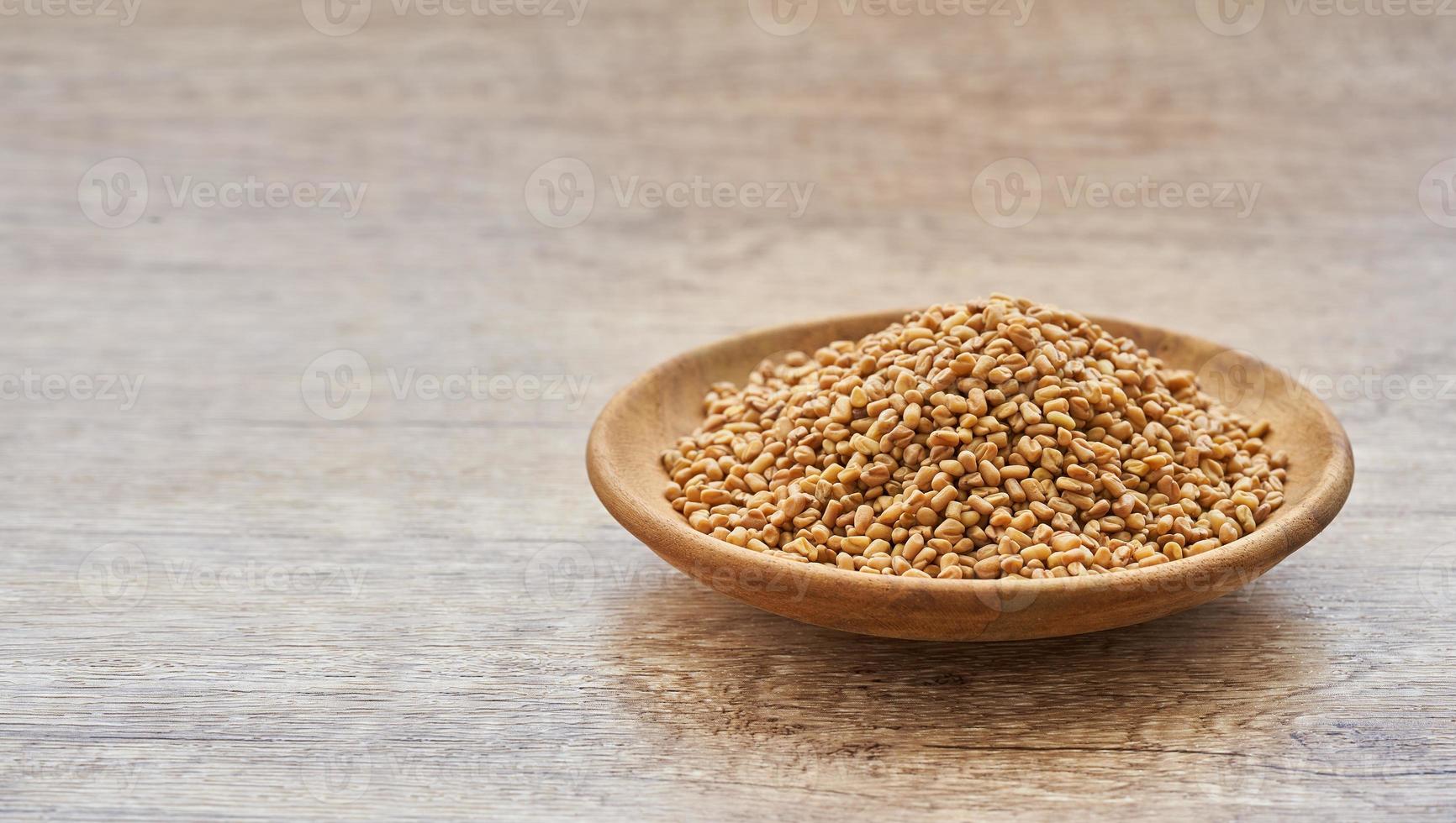 fenugreek seed in wood plate on wooden table background. fenugreek seeds background photo