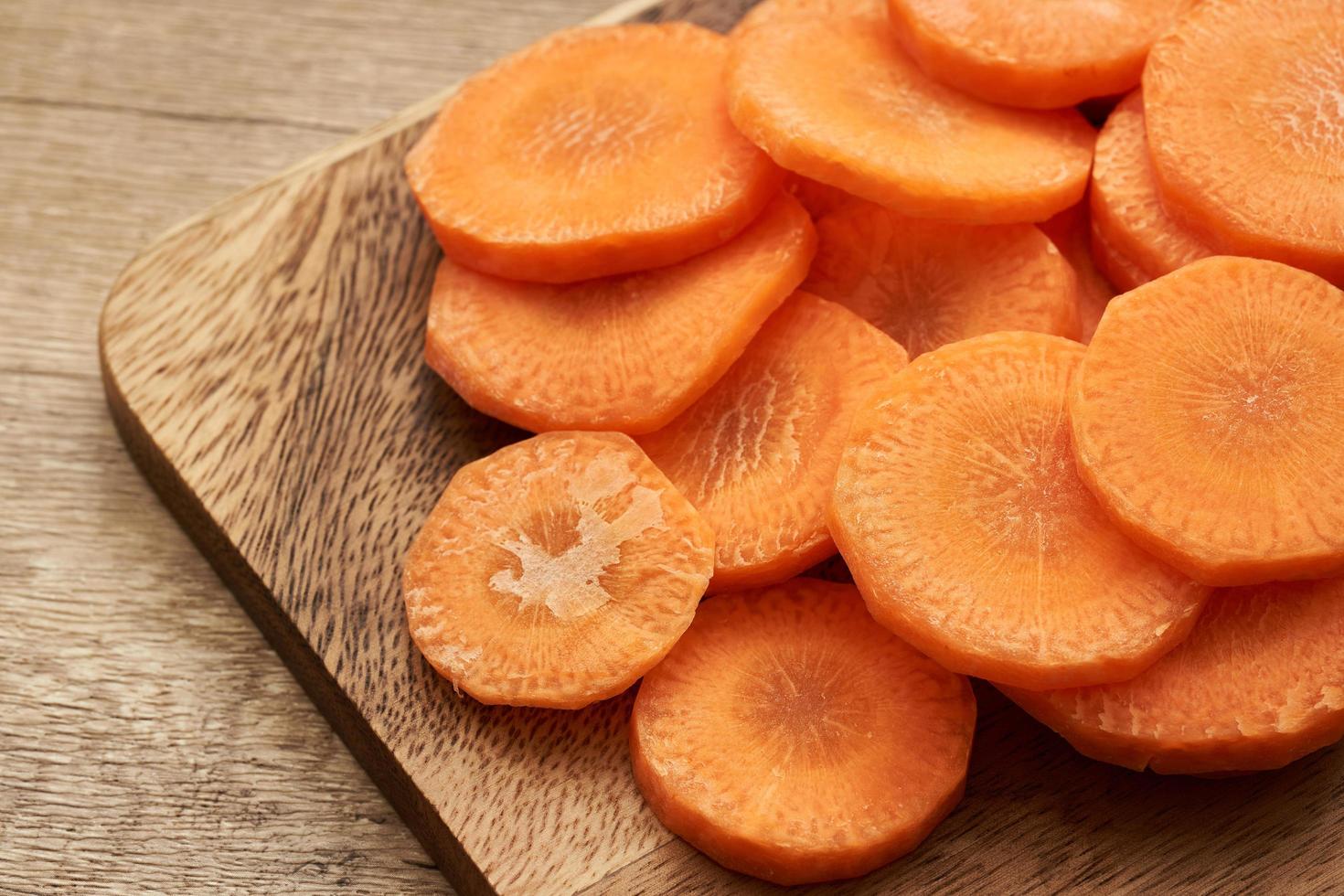 chop round carrot on wooden plate on wood table background photo