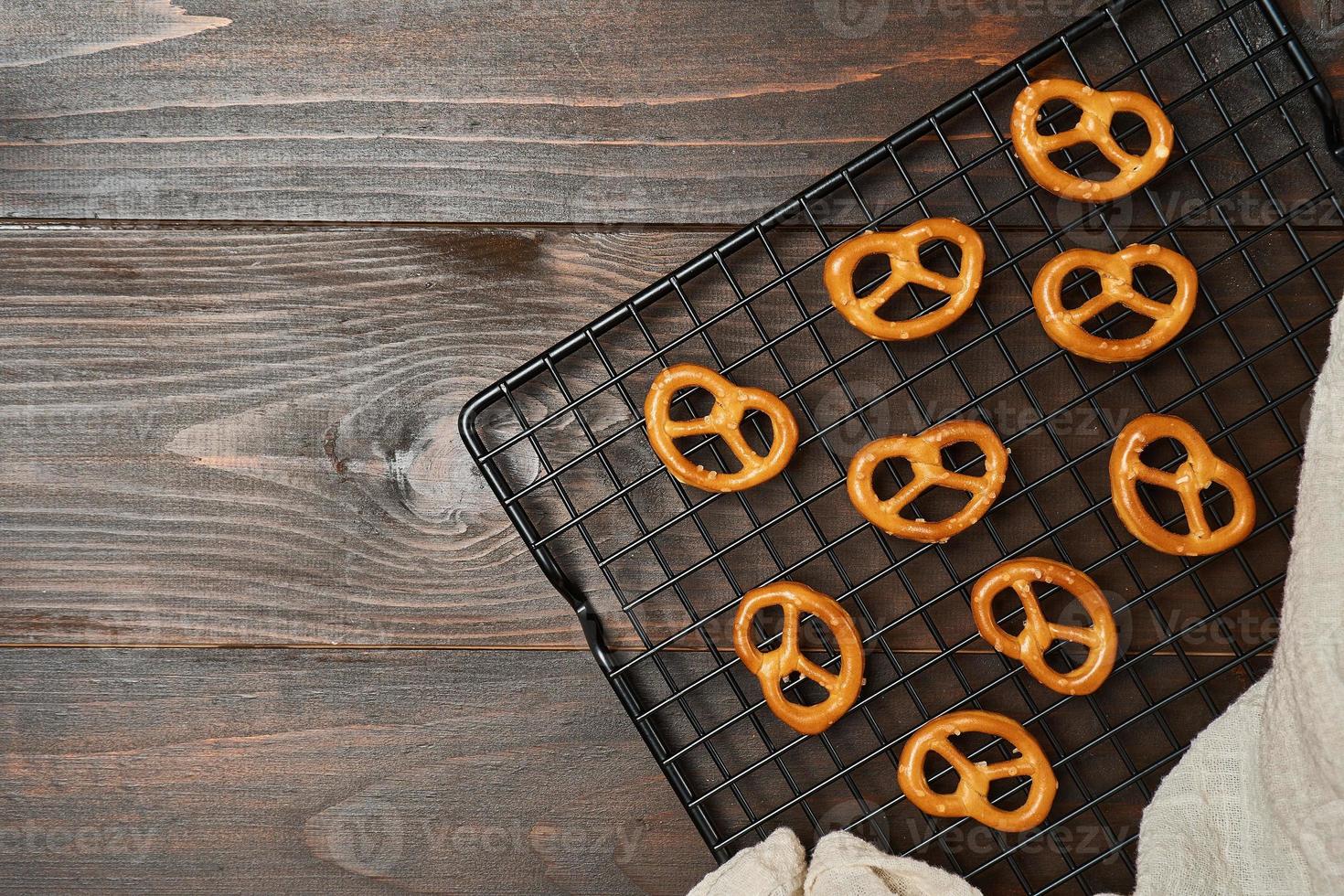 mini salted pretzels on wire cooling rack wooden background. hard crackers or snacks. top view, above photo