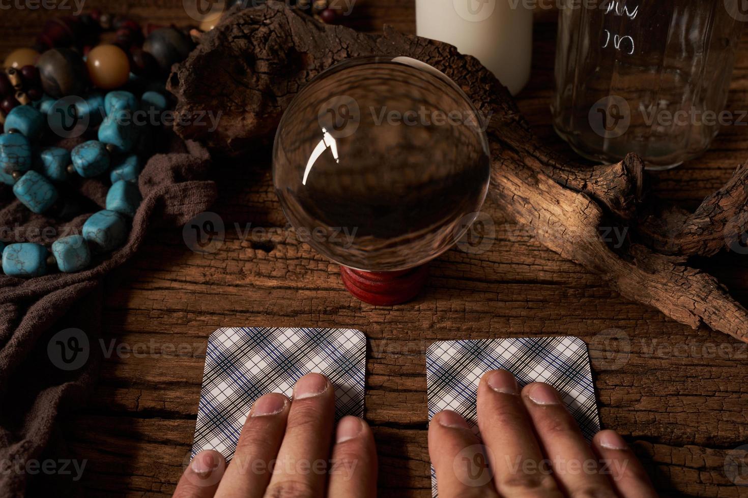 concept of fortune-telling on a wooden table and white candle with a crystal ball and tarot cards on dark background. hand photo