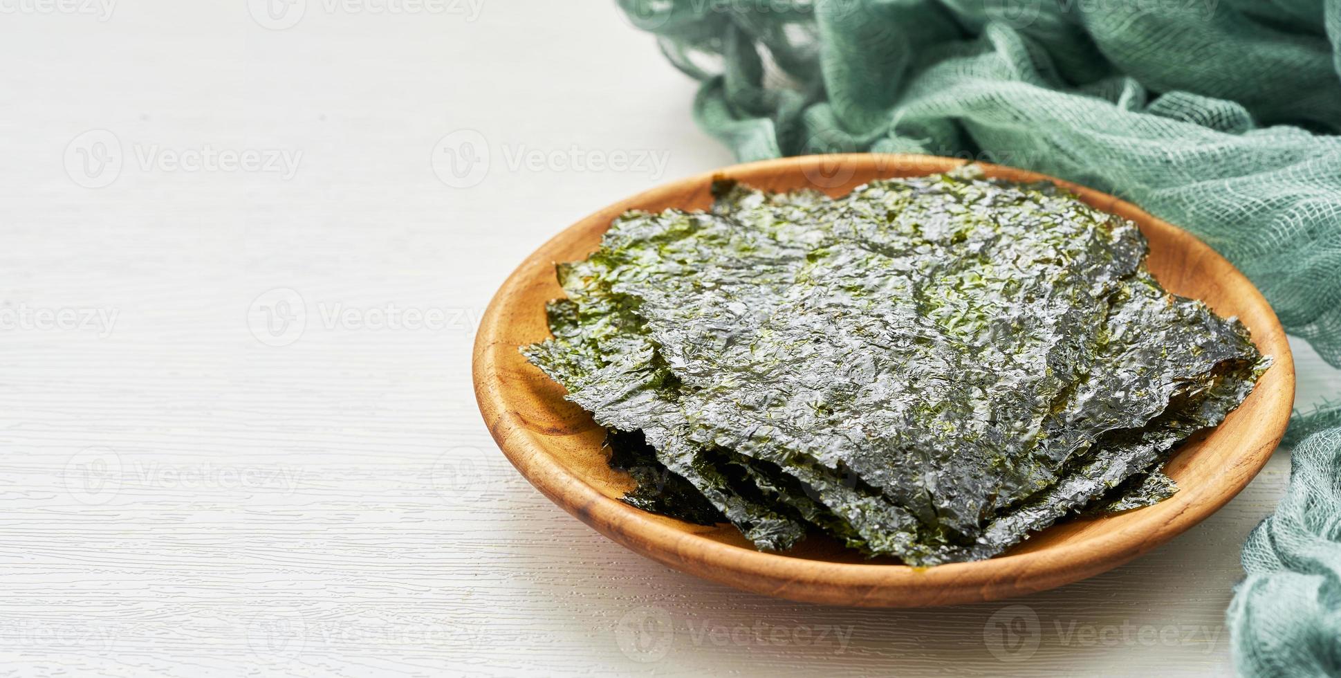 roasted nori laver seaweed snack in wood plate on white wooden table background. nori laver seaweed crispy in wood plate on white wooden table background photo