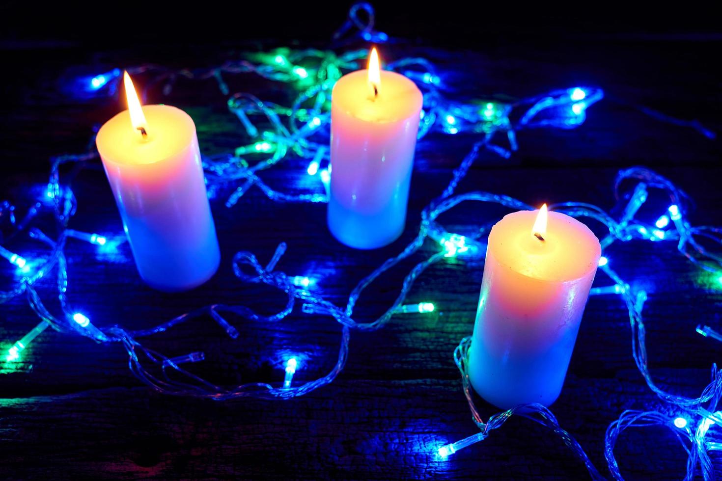 Flame candles with decorative lights on black table background photo