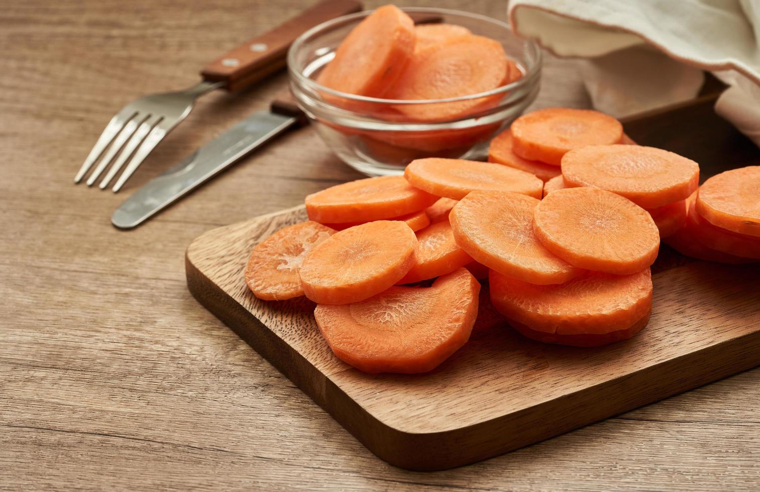 chop round carrot on wooden plate on wood table background photo