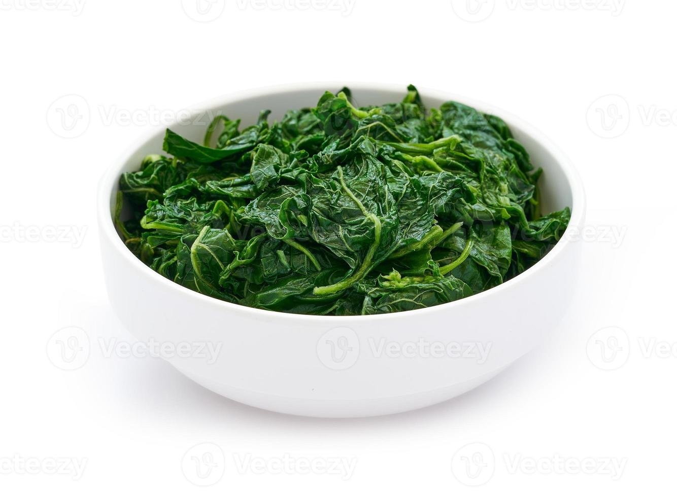 pile of green cook leaf spinach in white bowl isolated on white