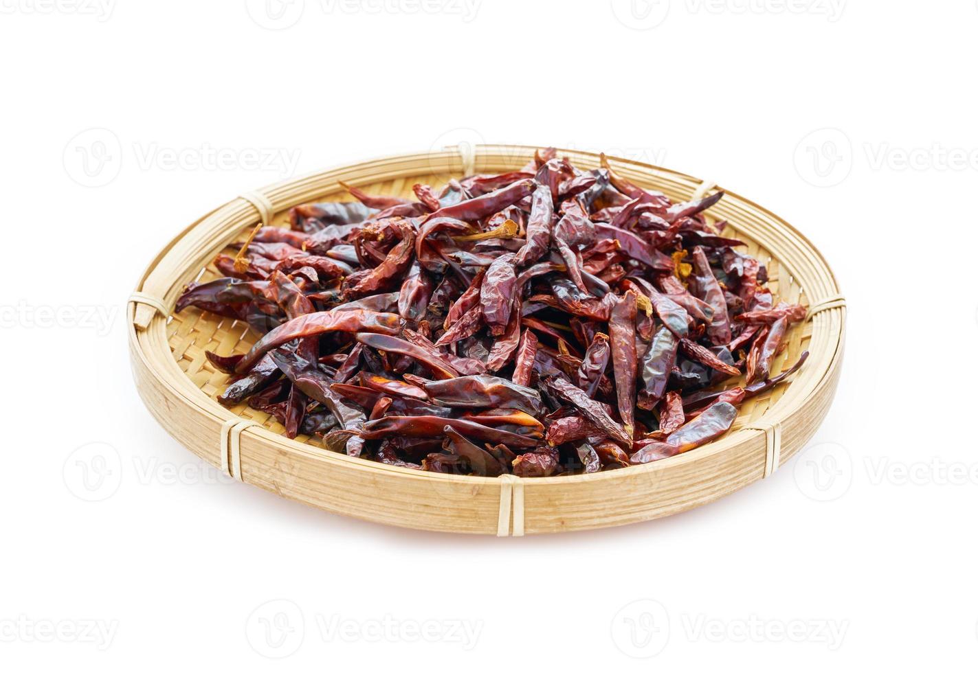 pile of dry red chilli chili pepper in wood bamboo plate isolated on white food spices background. chilli, chili, pepper photo