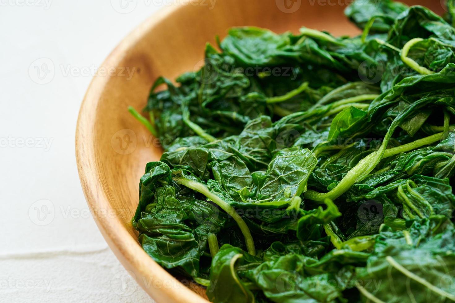 close up green cook leaf spinach salad in wood bowl on white table background. leaves spinach or heap of spinach food salad photo