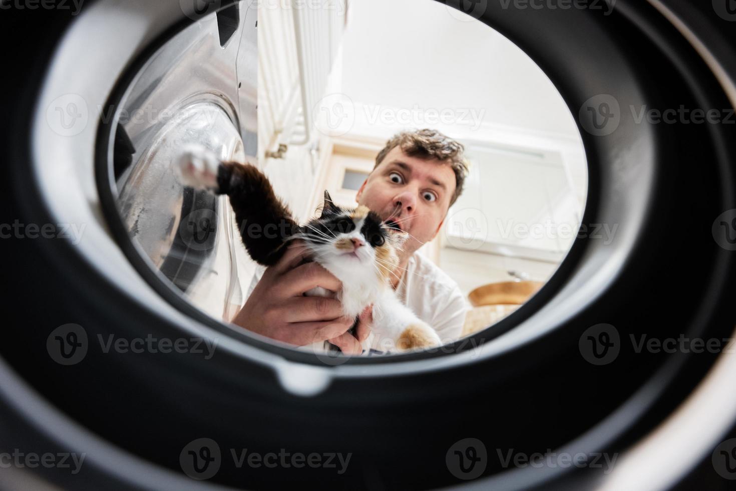Man with cat view from washing machine inside. Male does laundry daily routine. photo