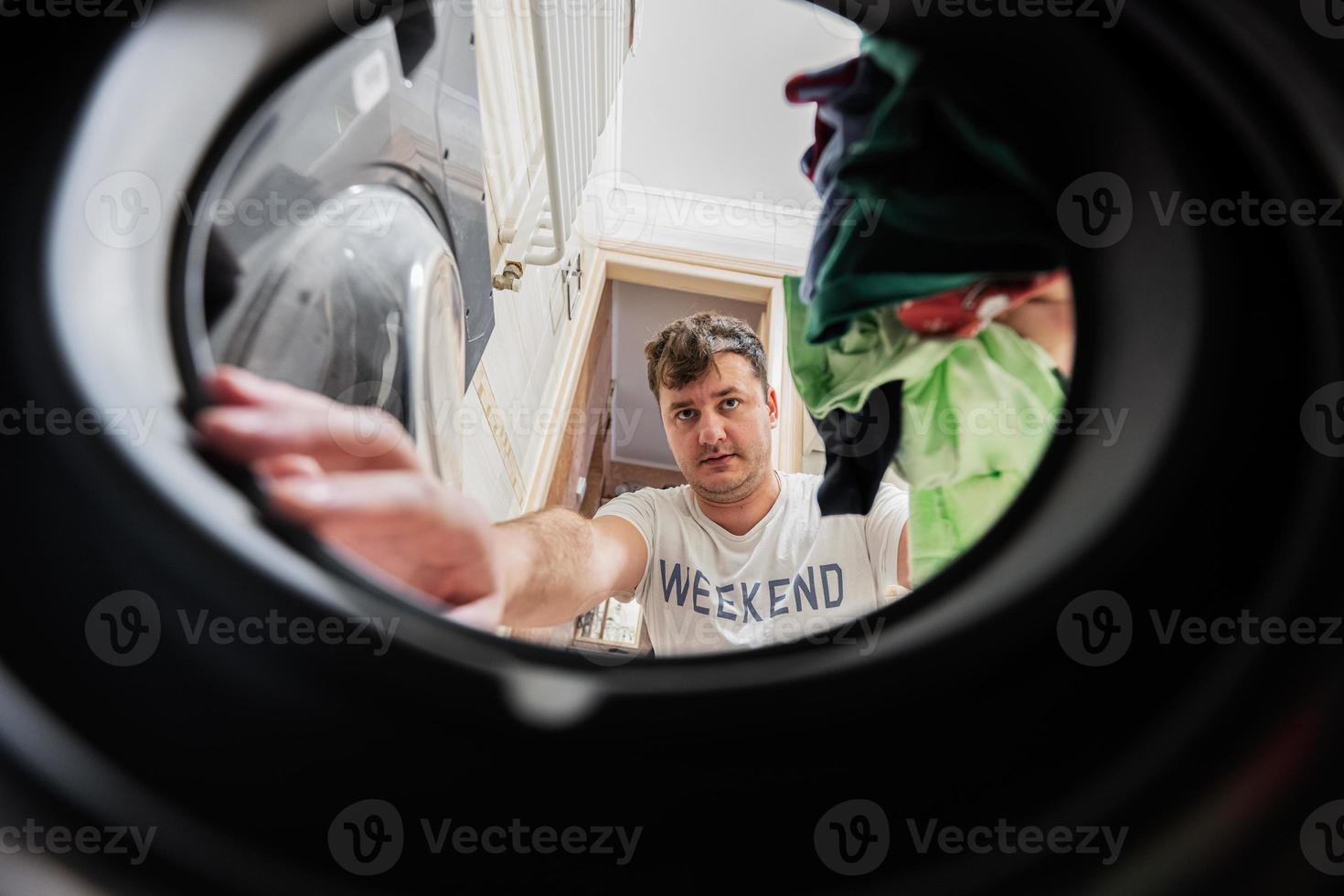 hombre ver desde Lavado máquina adentro. masculino lo hace lavandería diario rutina. foto