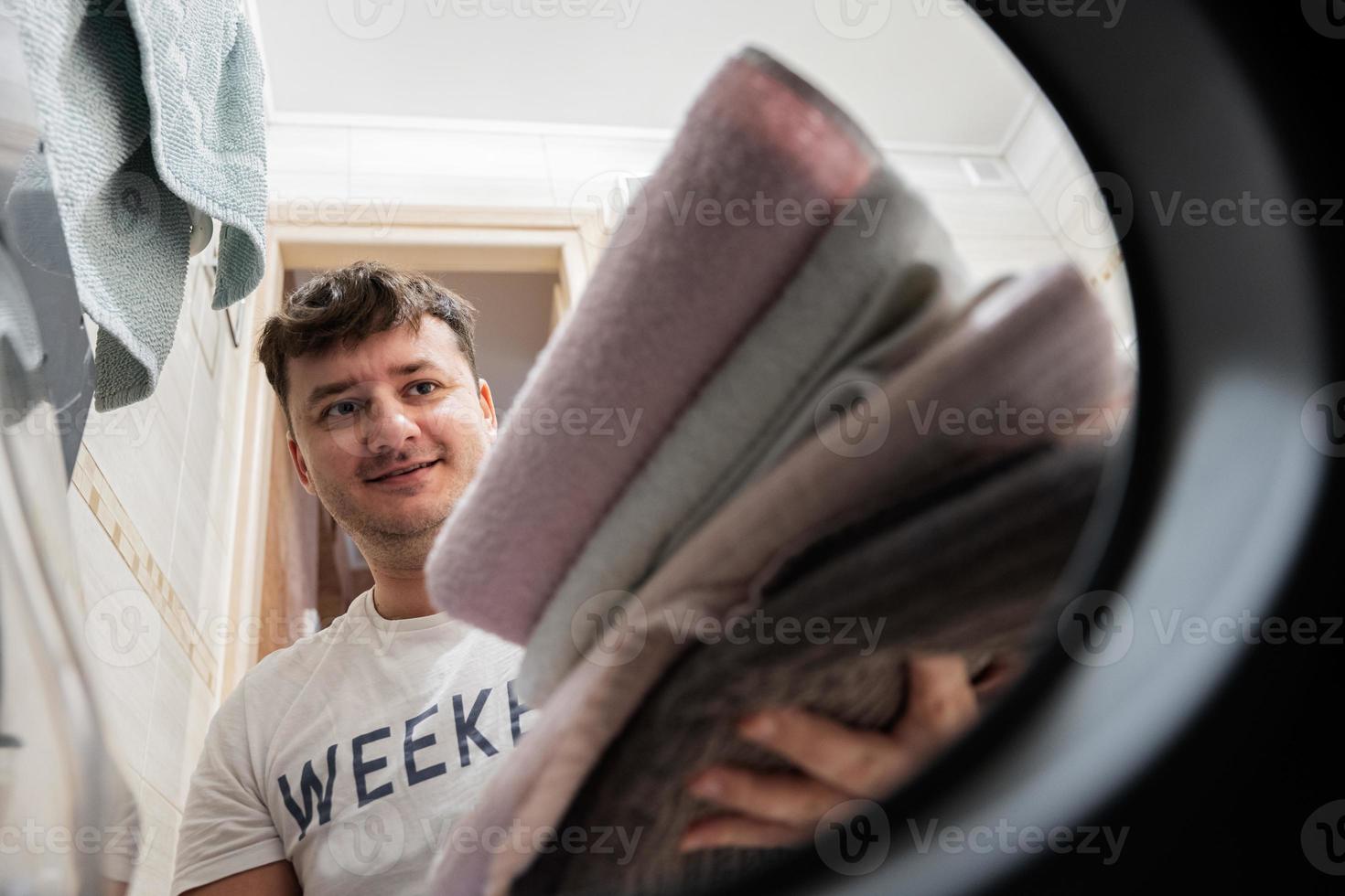 Man view from washing machine inside. Male does laundry daily routine. photo