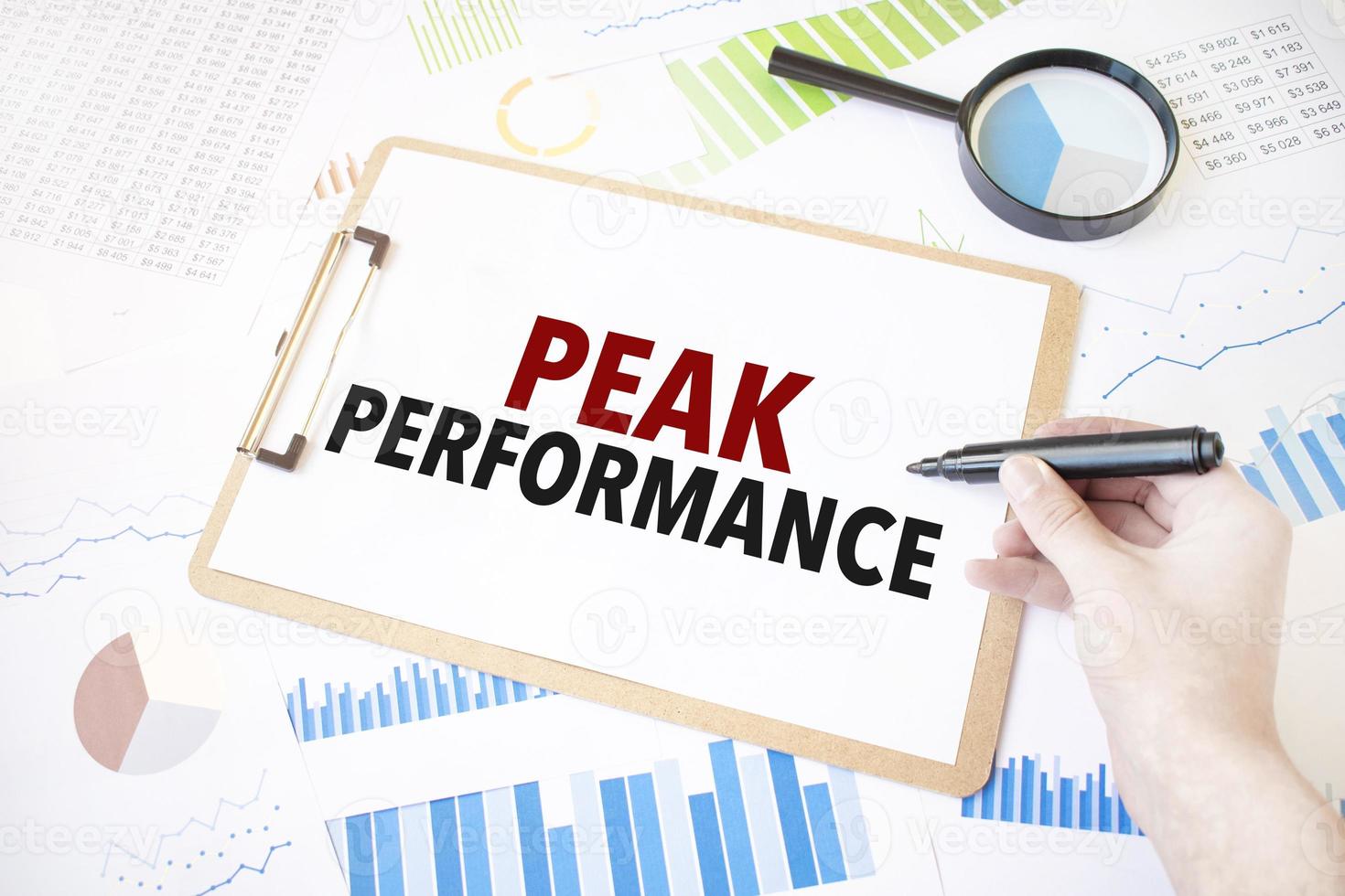 Text peak performance on white paper sheet and marker on businessman hand on the diagram. Business concept photo