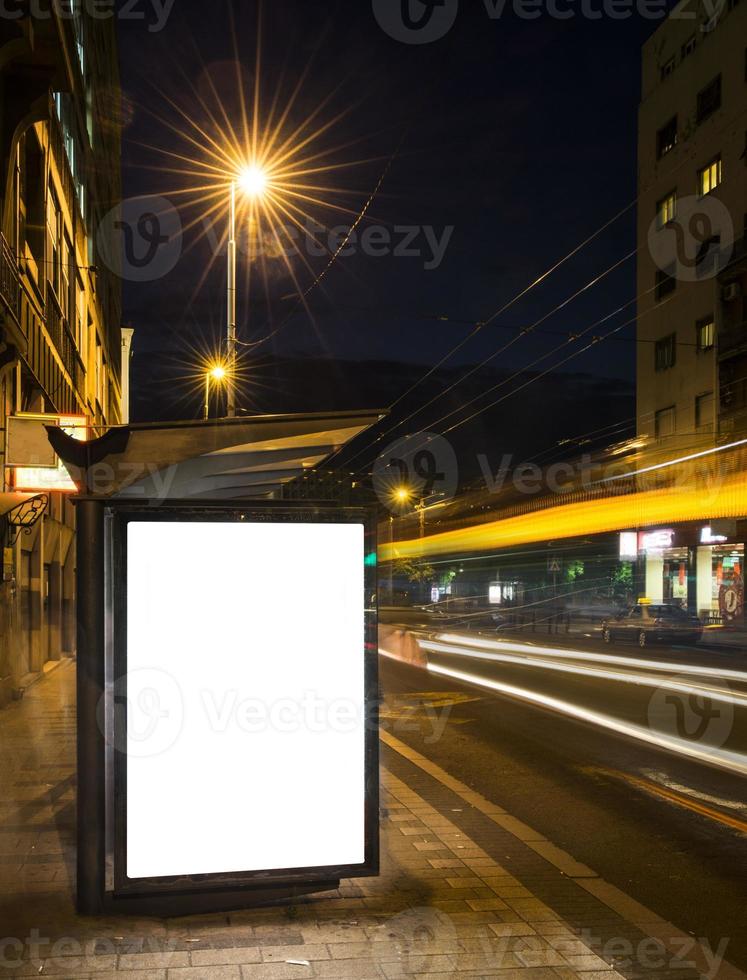 Night bus station with blank billboard photo