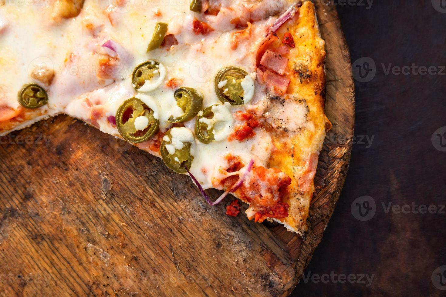 Pizza on a wooden board with a slice missing photo