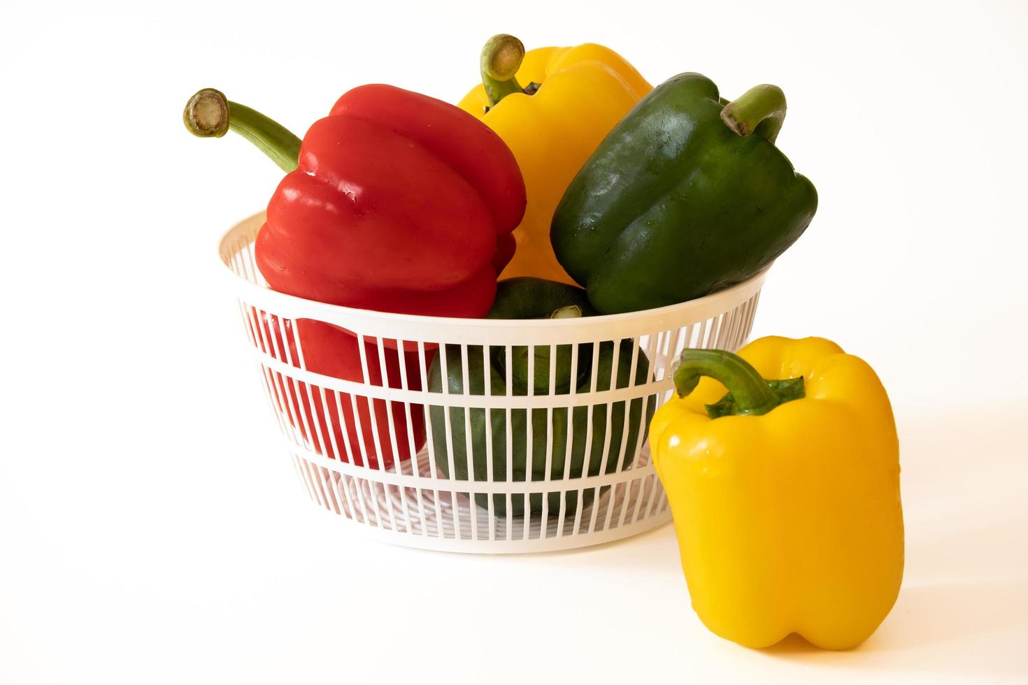 Sweet bell peppers in the white basket with water drops isolated on white background. photo