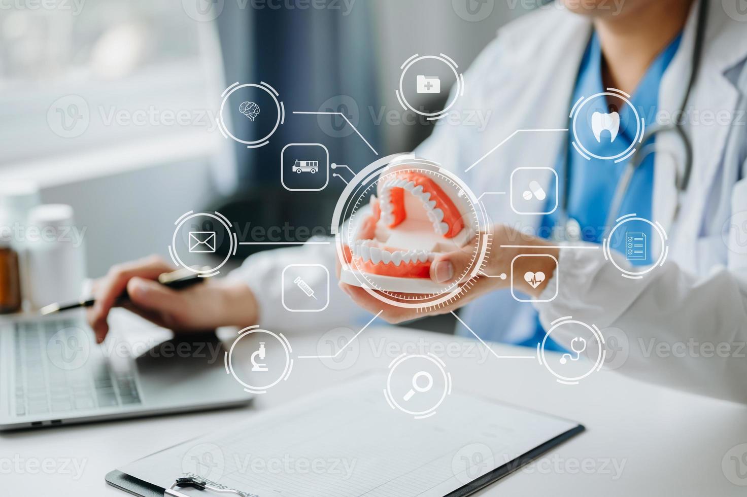 Dentist sitting at table with jaw samples tooth model and working with tablet and laptop in dental office professional dental clinic. medical doctor working photo