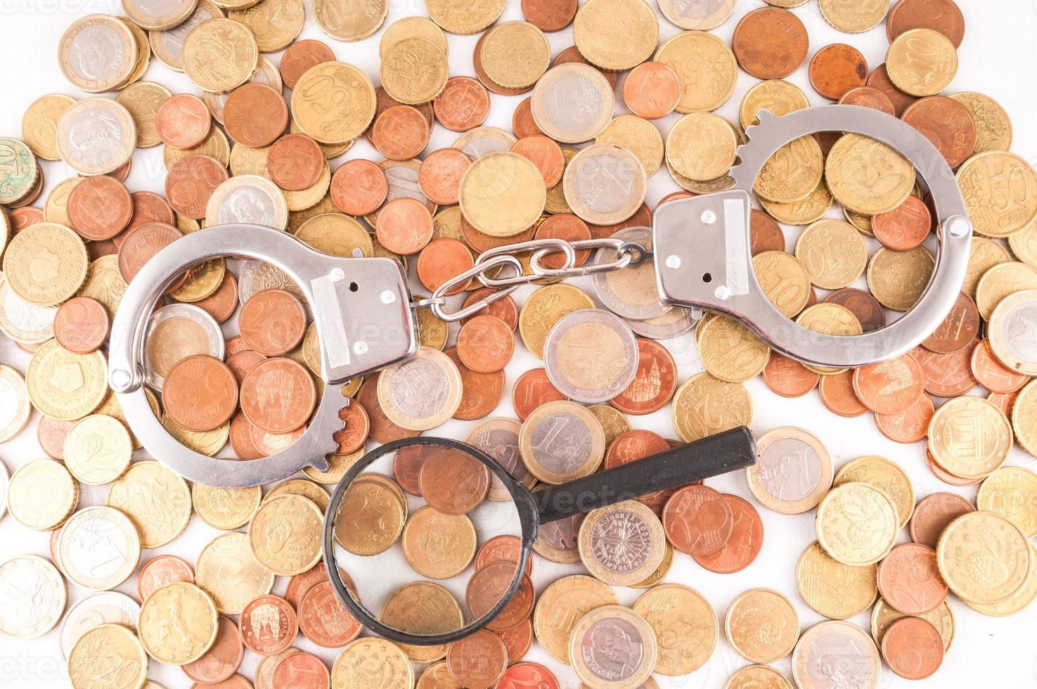 Coins, loupe and handcuffs photo