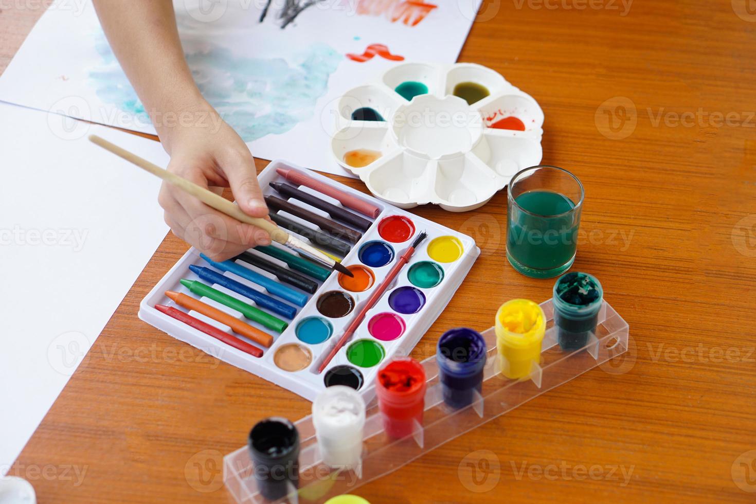 Closeup student is studying art subject, painting, art activity, enjoy and concentrate on favorite activity with many colors. Concept, Education. Learning by doing, enhance kid's imagination. photo