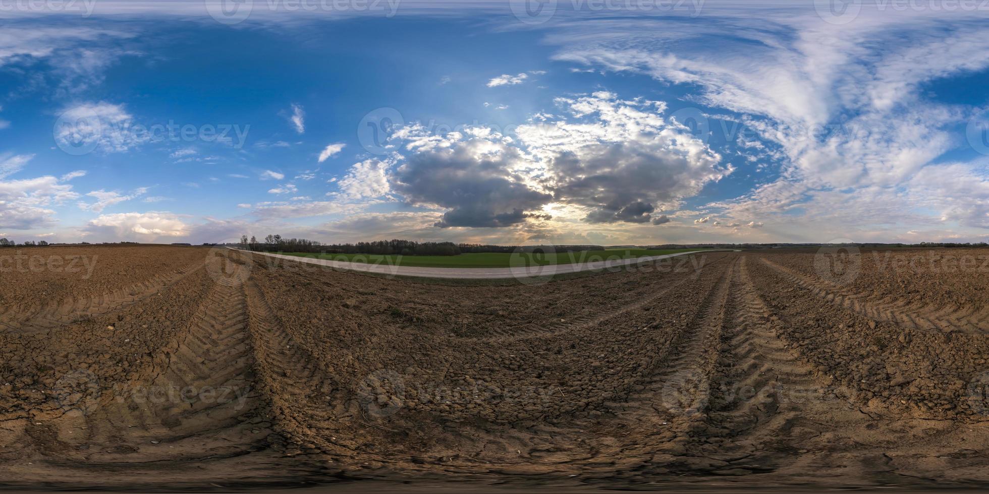 360 hdri panorama view among fields with sunset sky in golden hour in countryside with tractor tires in equirectangular seamless spherical projection.  use like sky replacement for drone shots photo