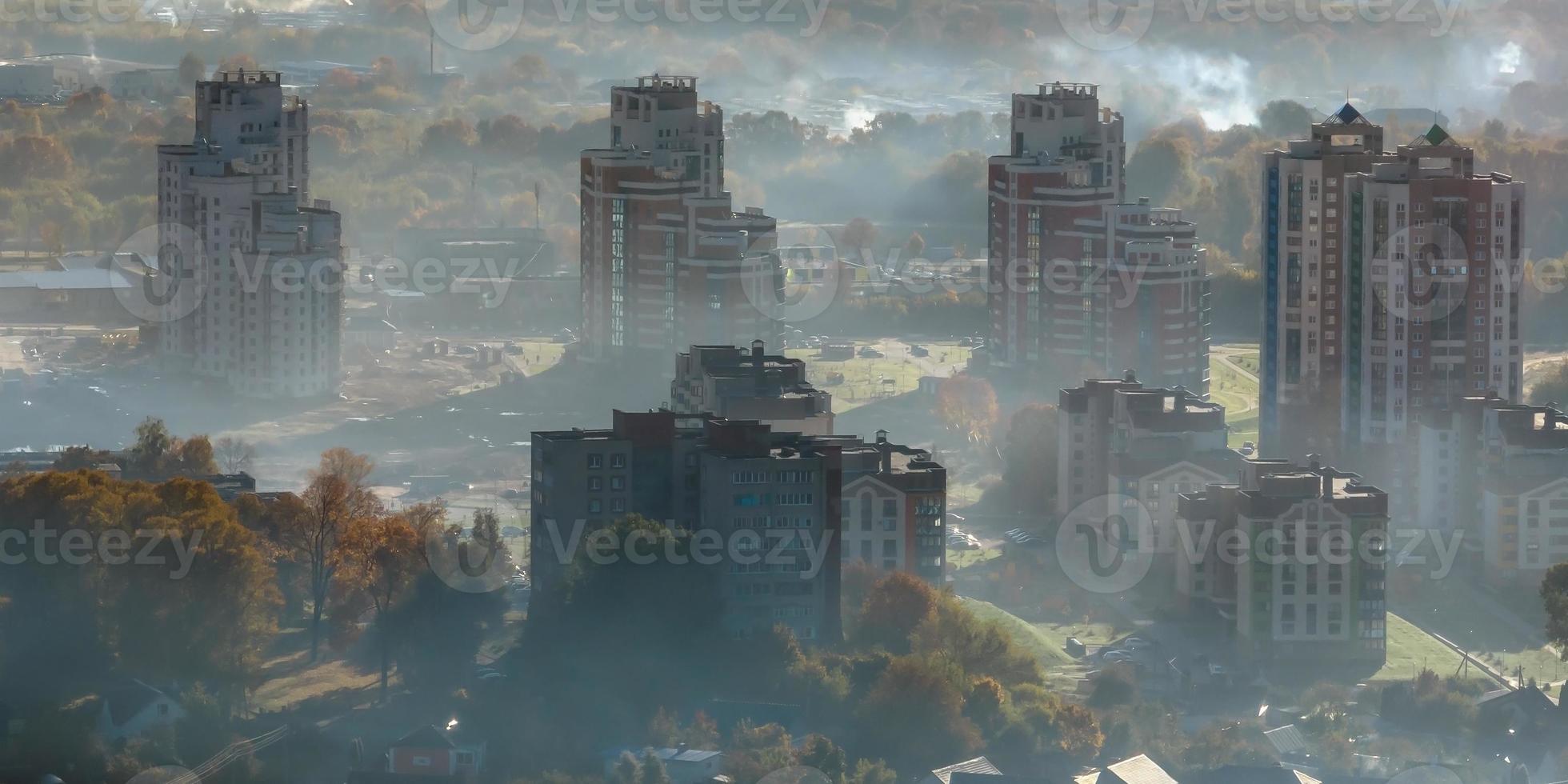 aerial view of green city with skysrapers and residential buildings in earning fog and mist photo