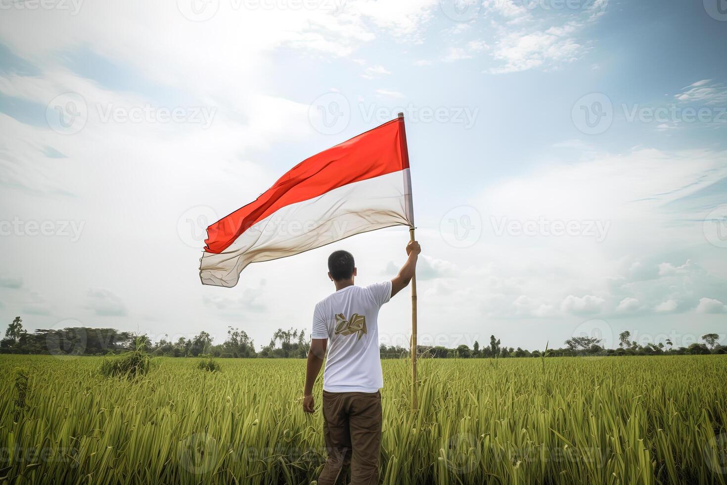 un hombre participación un rojo y blanco Indonesia bandera en parte superior de un lozano verde arroz campo. ai generado foto