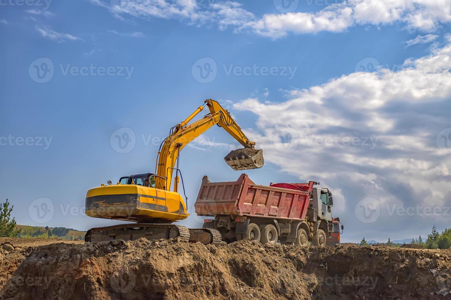 Yellow excavator and empty dump truck working at the construction site photo