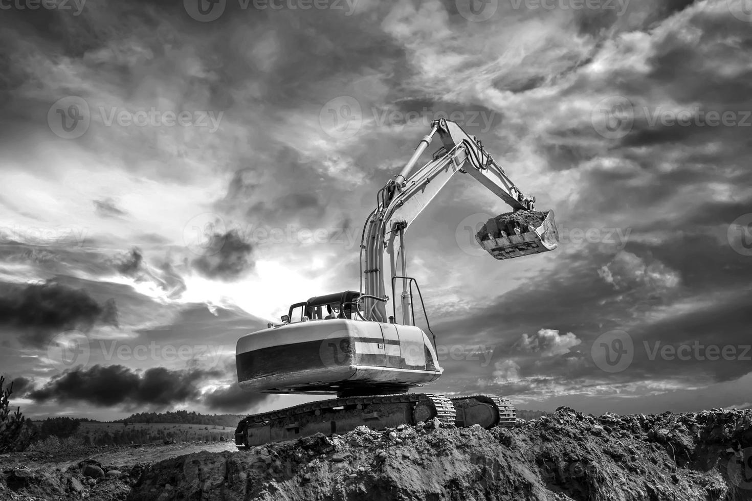 Crawler excavator during earthmoving works on construction site in black and white photo