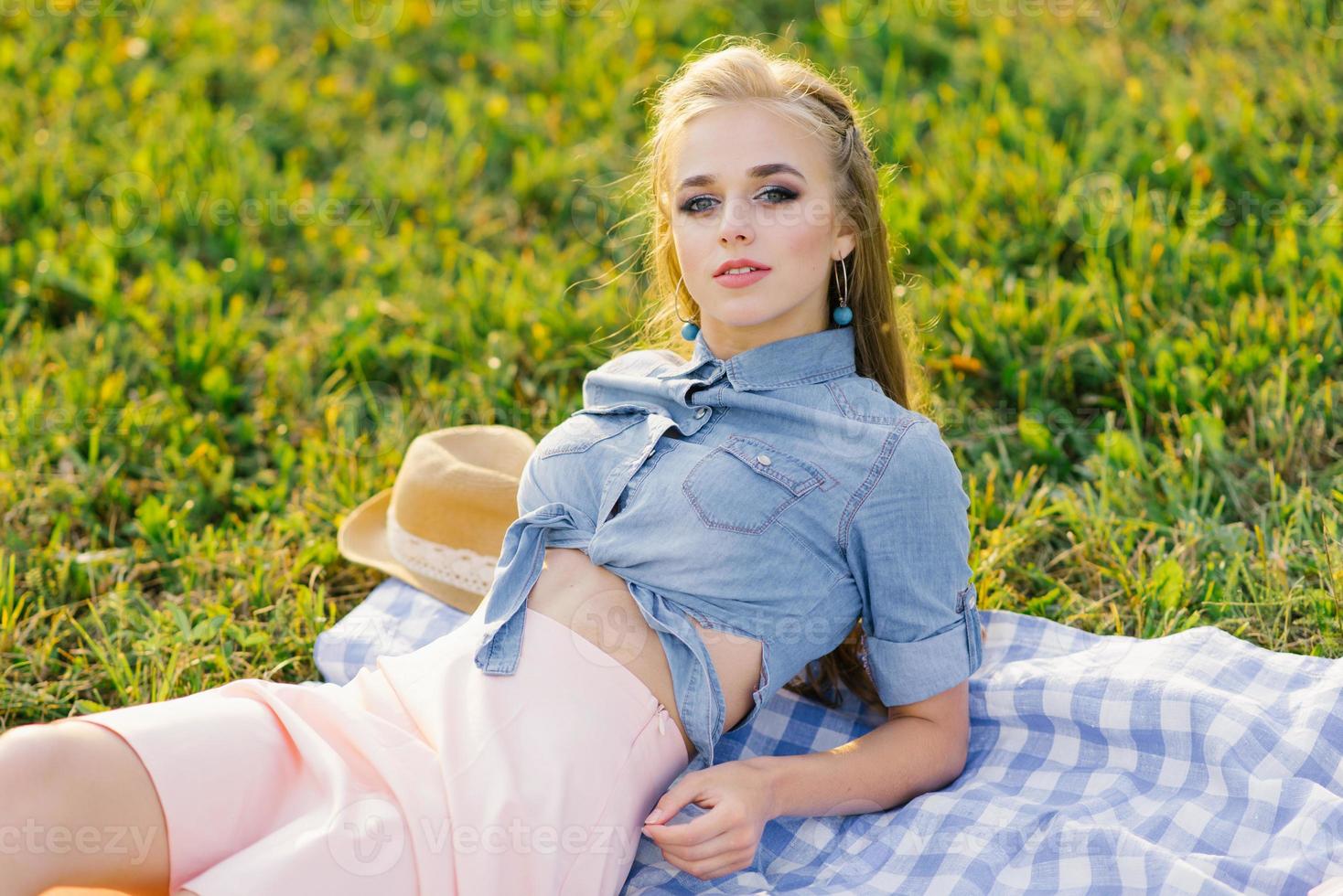 Young woman lying on a blue plaid blanket in a city park and enjoying the sunny weather photo