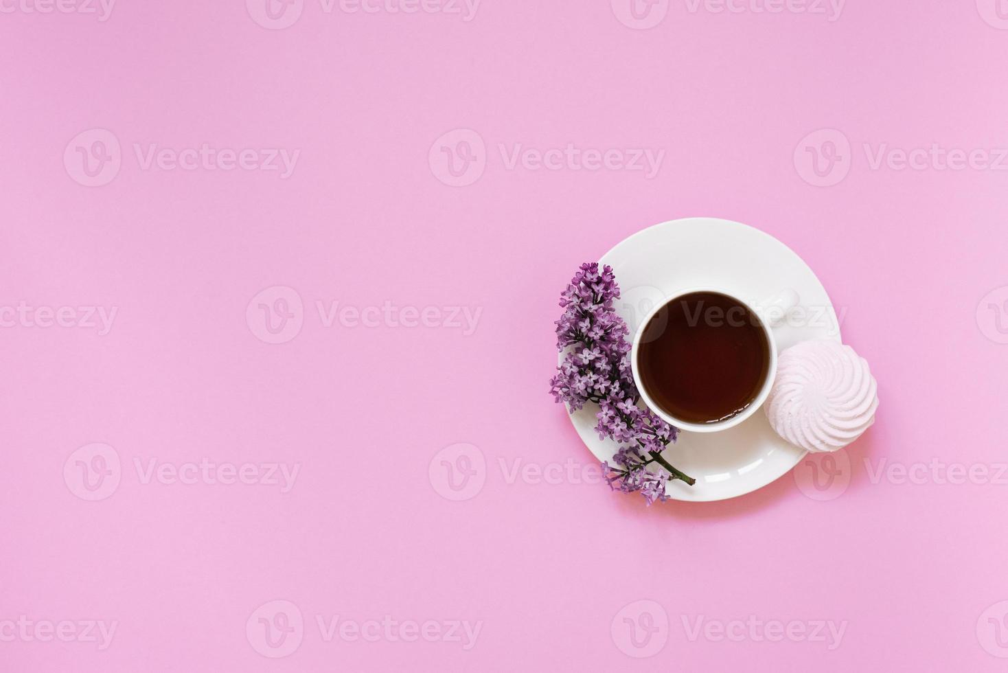 Flower arrangements of beautiful purple lilac on a pink background with a cup of tea. Women's office desk, stylish stock image, Flat layout, top view with Empty copy space photo