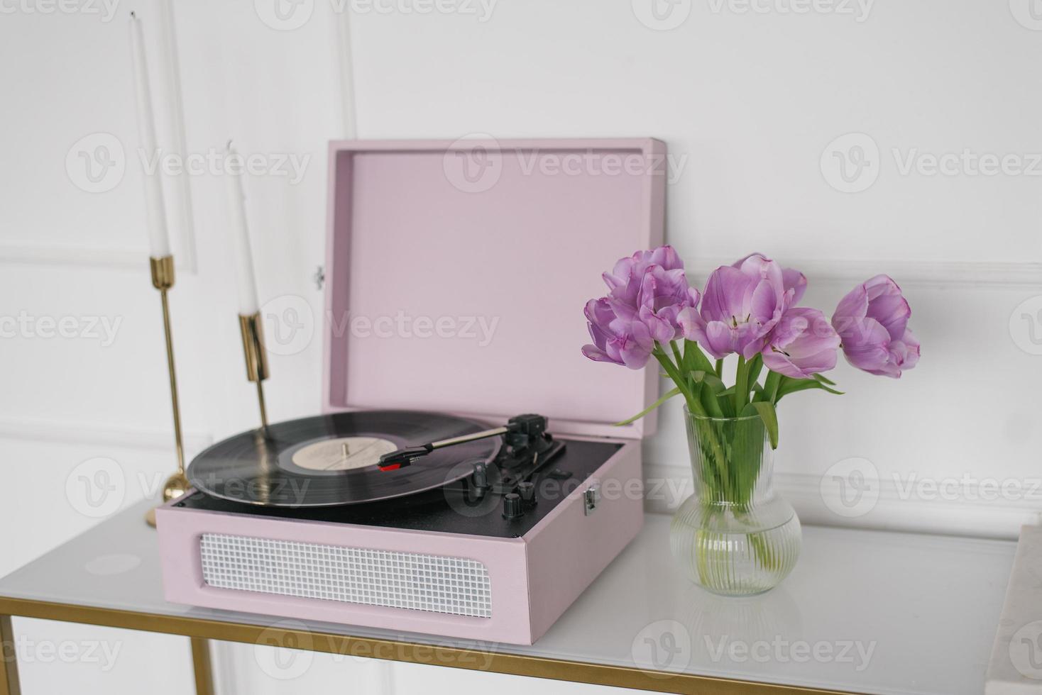 Beautiful lilac tulips in a glass vase, retro record player and candles in the living room photo