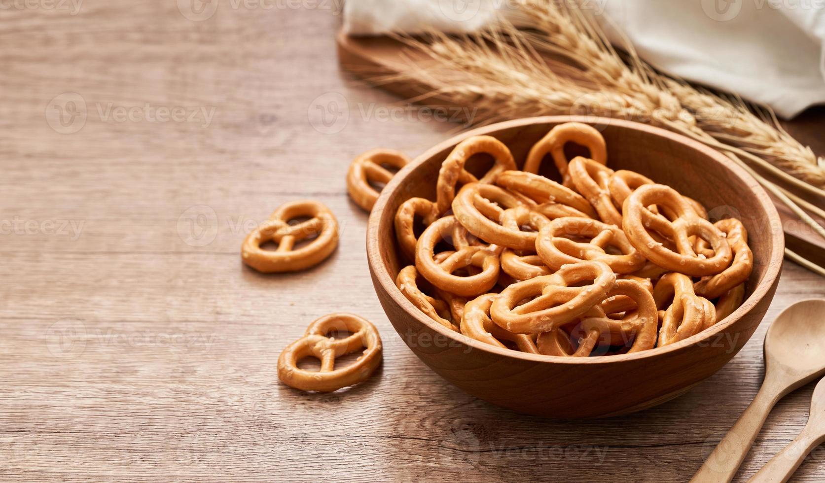 mini salted pretzel in a wooden bowl with a spoon and fork on wood table background. copy space photo