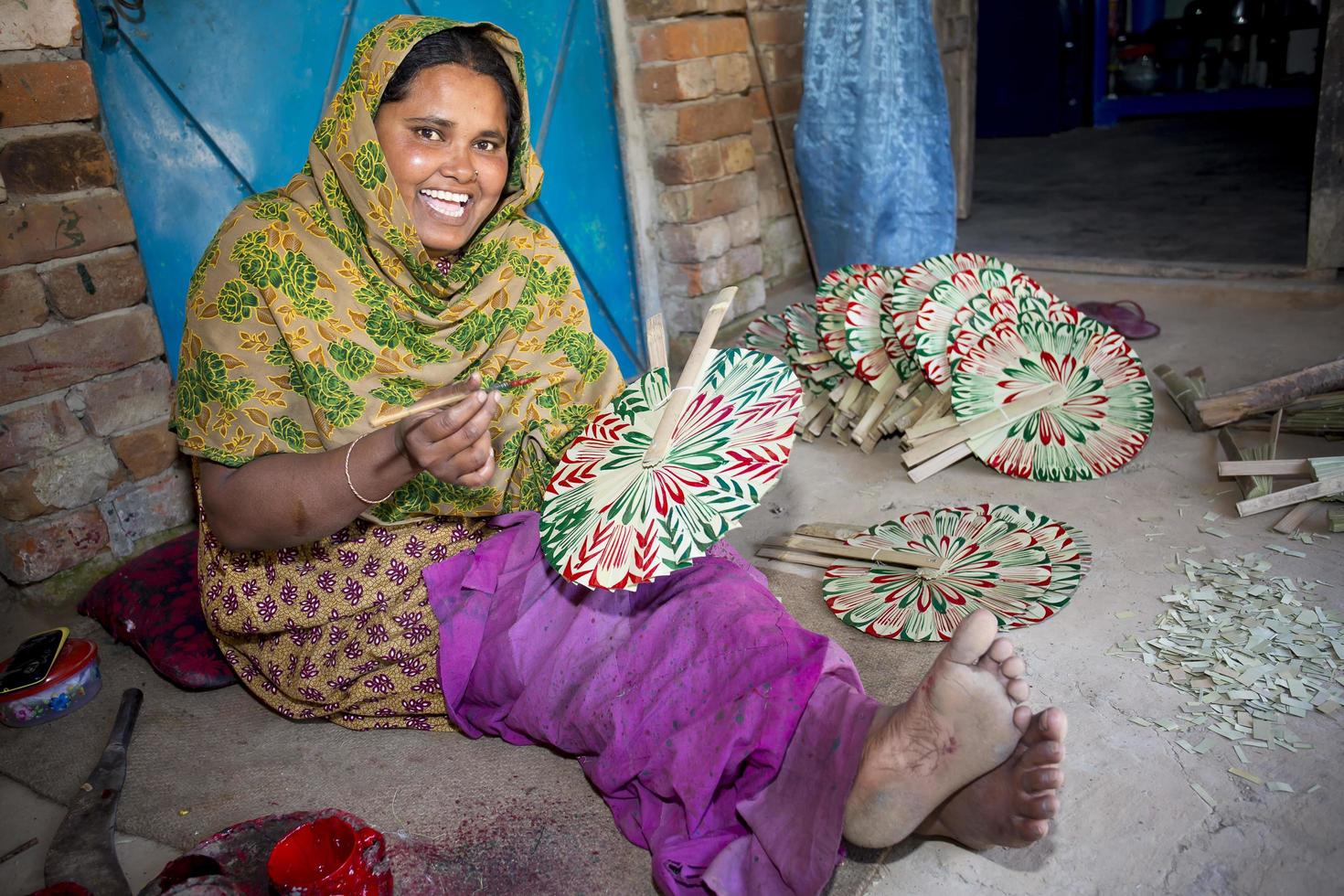 Bangladesh febrero 15, 2018 un mujer artesano es colorante un tradicional hecho a mano palma hoja ventilador con un color Cepillo de pintura a bogura, bangladesh foto