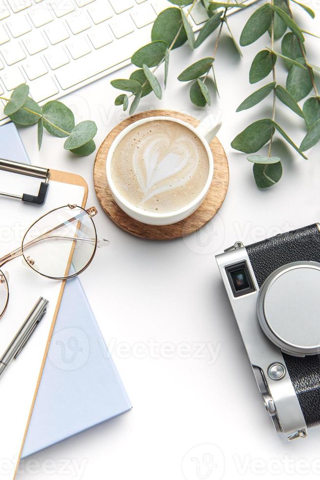 Modern white office desk table with laptop, camera, notebook and other supplies. photo