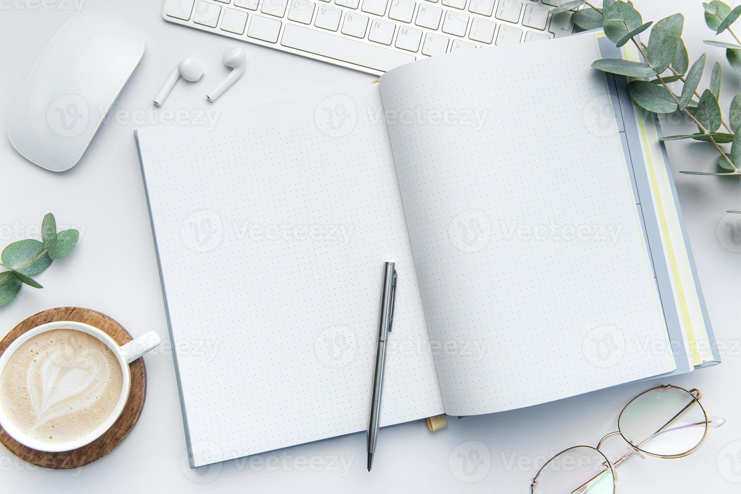 Modern white office desk table with laptop, notebook and other supplies. photo