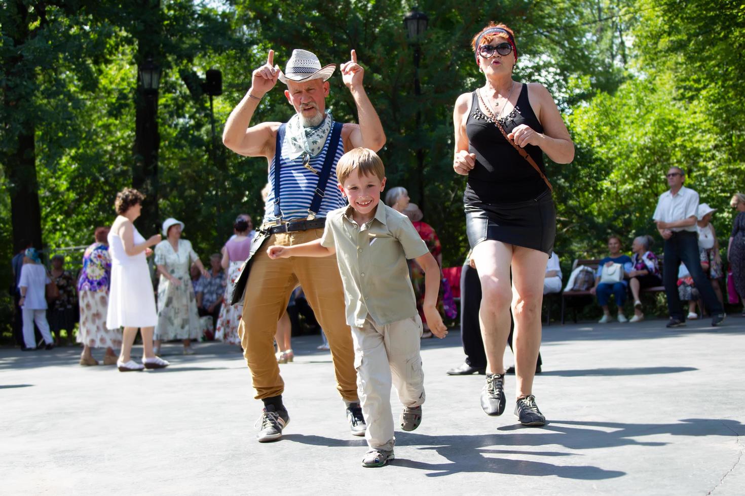 Cheerful grandparents are dancing with their grandson. photo