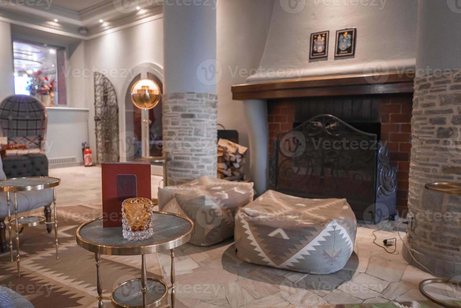 Book and decor on table with empty ottomans by fireplace in hotel room photo