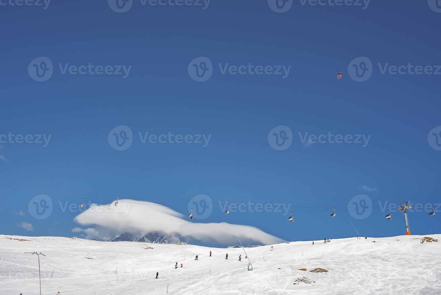 Skiers skiing on slopes and ski chair lifts over snowy mountain photo