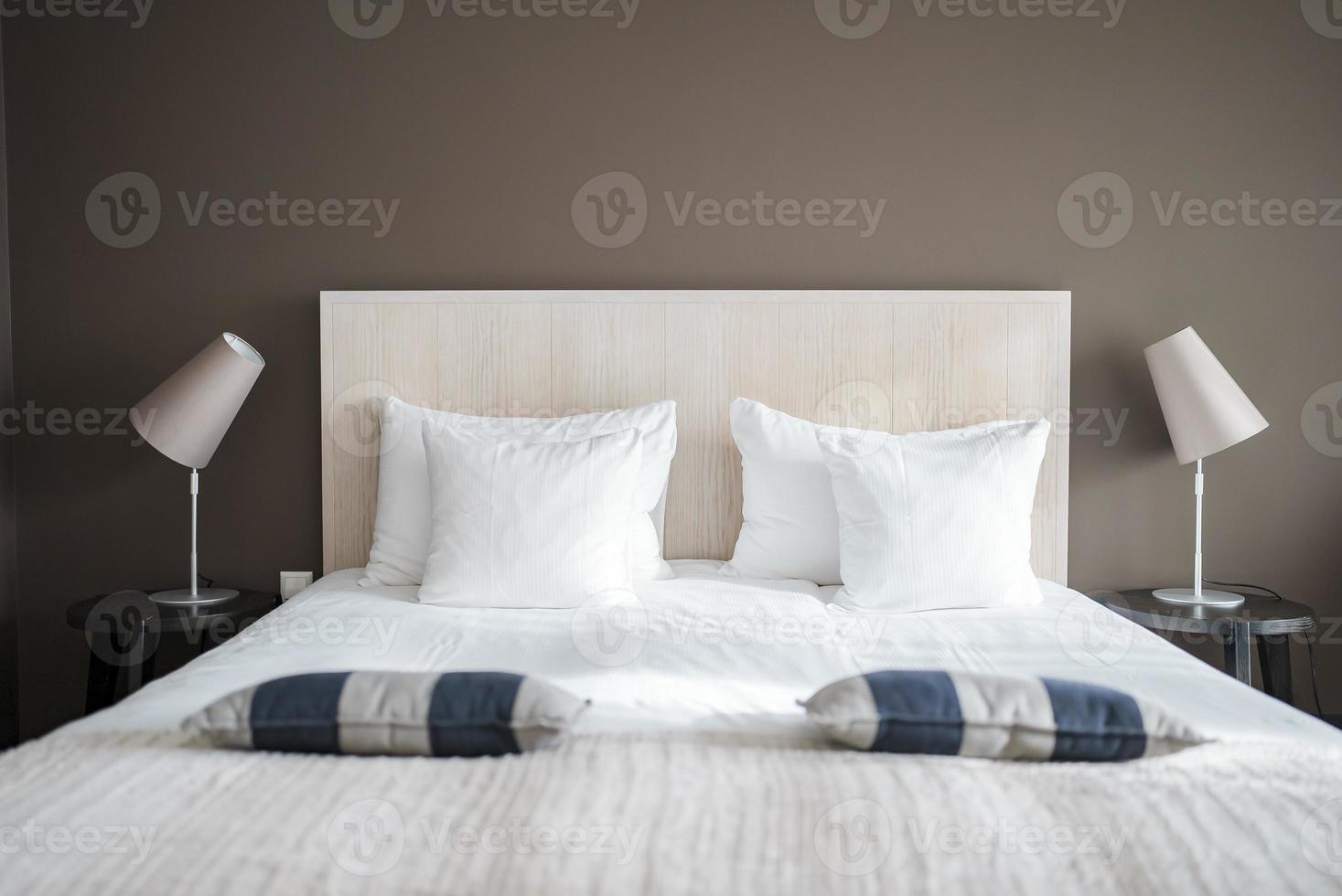 Pillows and cushions on bed with lamps on night tables in suite photo