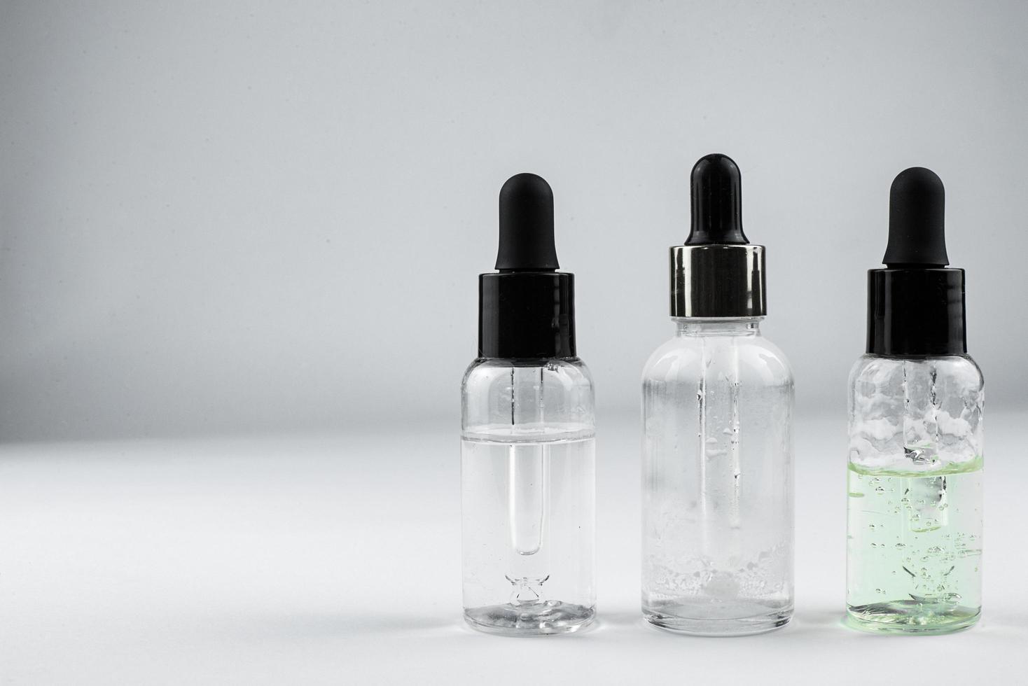 three glass bottles of cosmetic serum on a light background photo