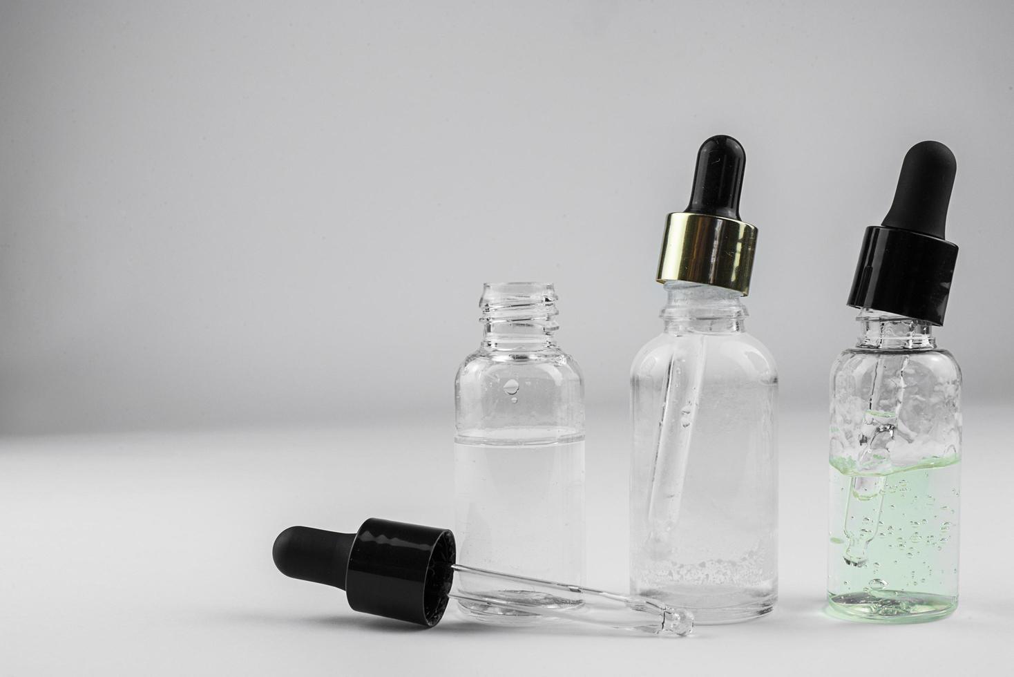 three glass bottles of cosmetic serum on a light background photo