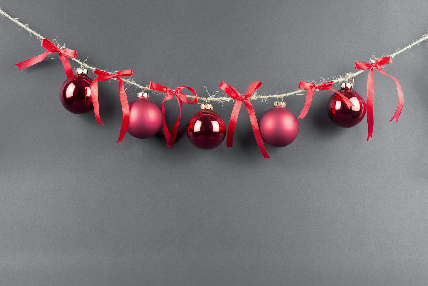 thread with red christmas balls and red bows on black background photo