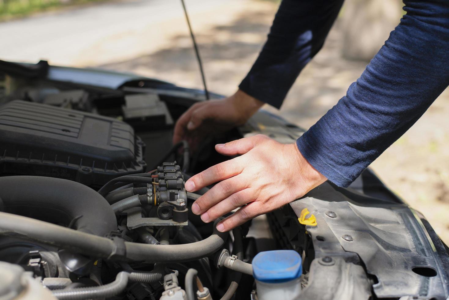 A man on the side of the road is fixing a car. Hands on the hood. Car repair on the road. Machine breakdown. photo