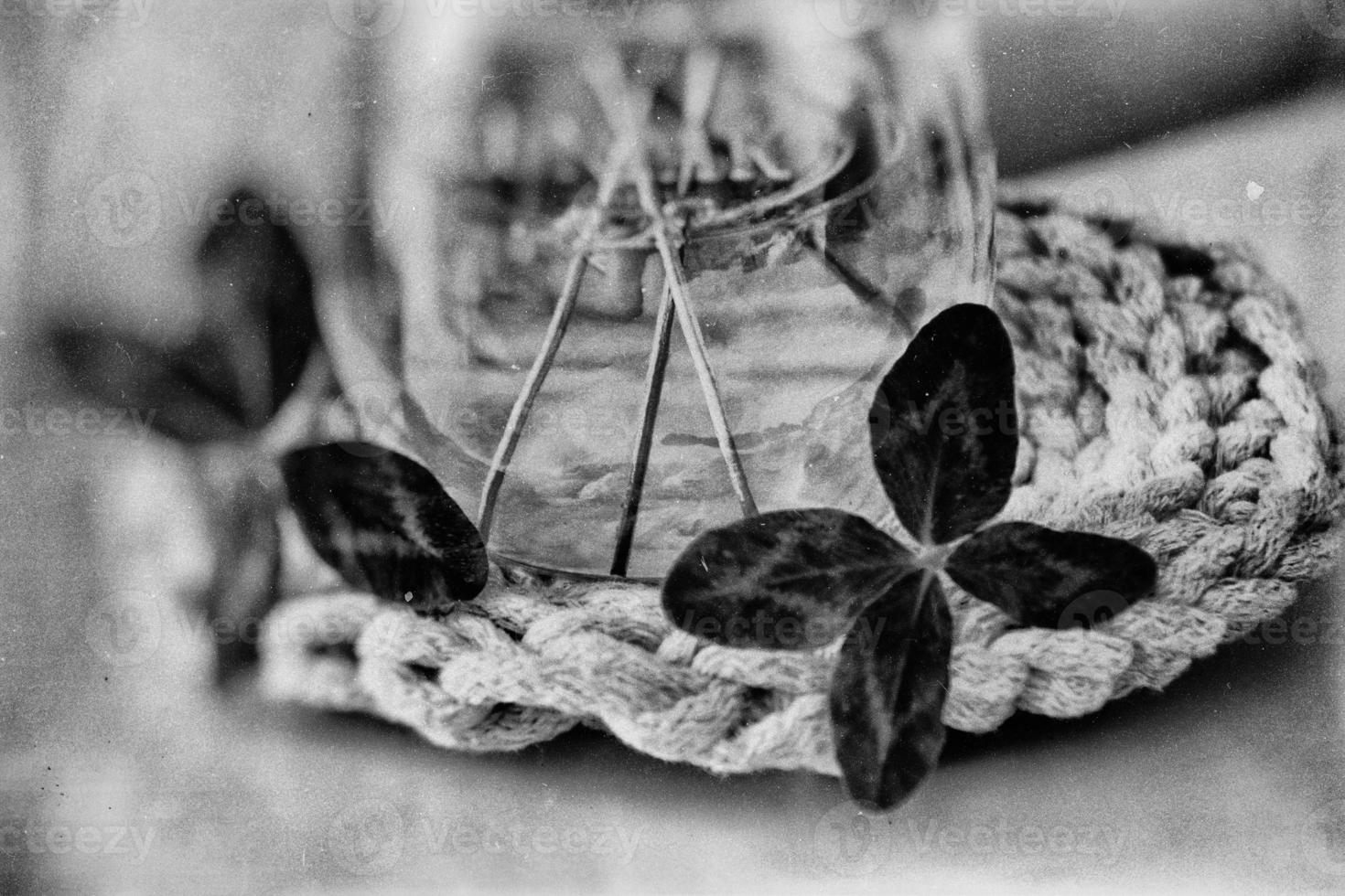 un ramo de flores de l campo cuatro hojas tréboles en un pequeño florero en un ligero suave antecedentes foto