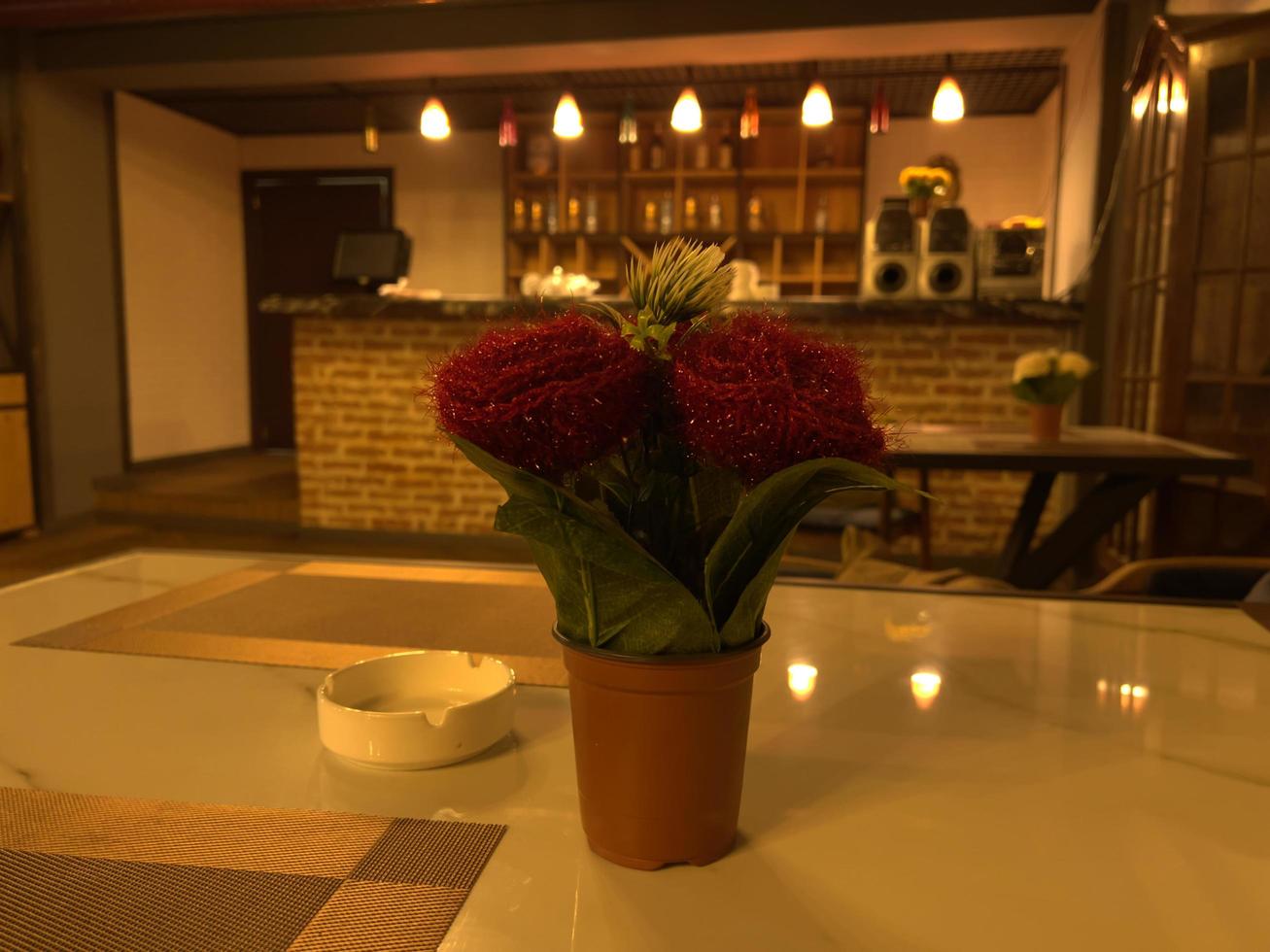 Coffee table in a restaurant with red flowers in a vase photo
