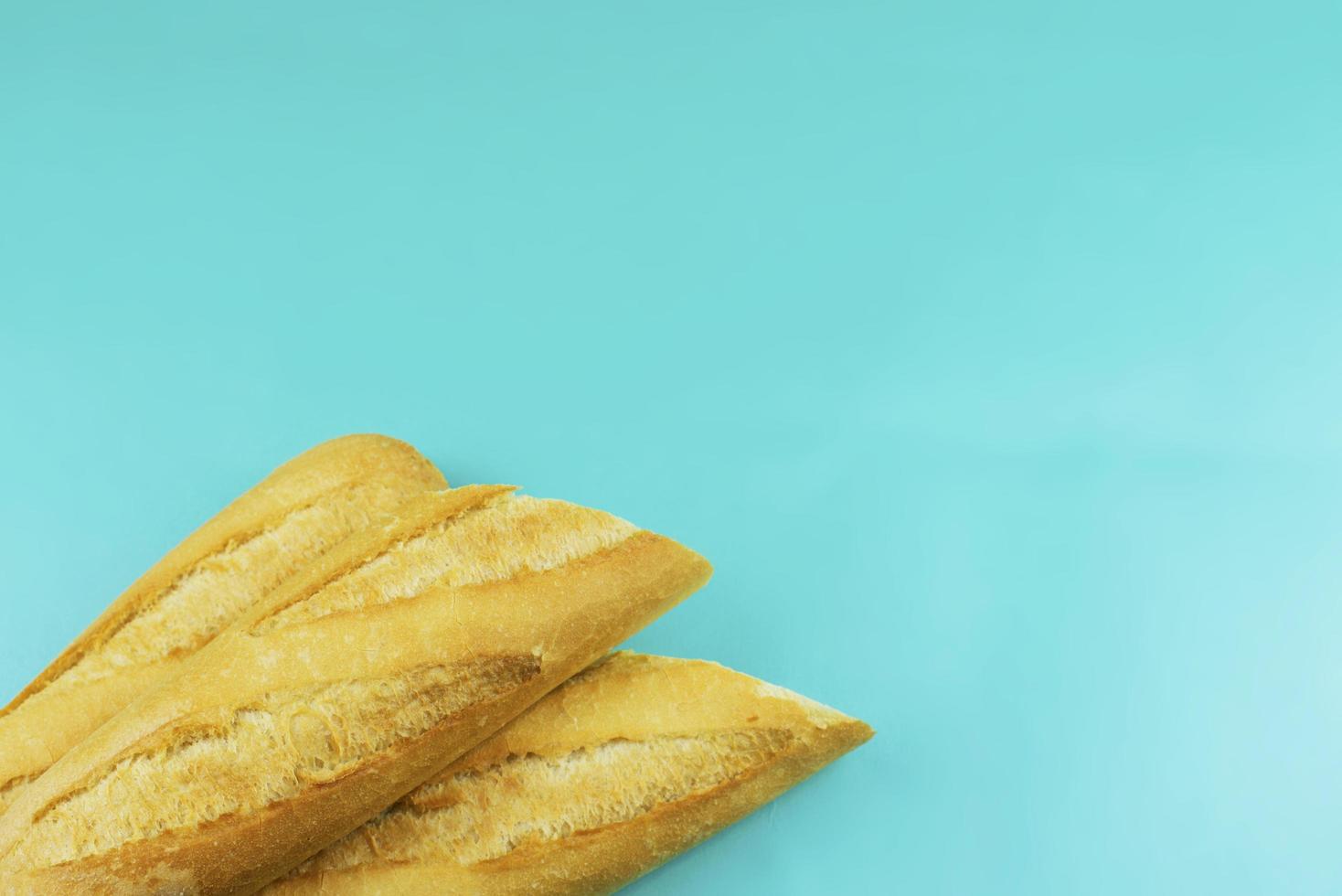 three French baguettes in the left lower corner on a light blue background photo
