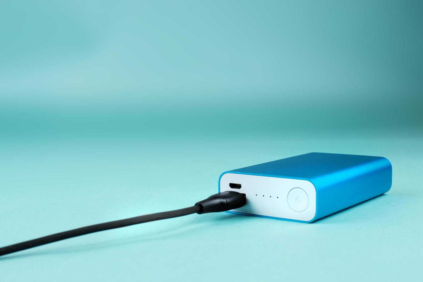 blue power bank with black cable on blue background photo