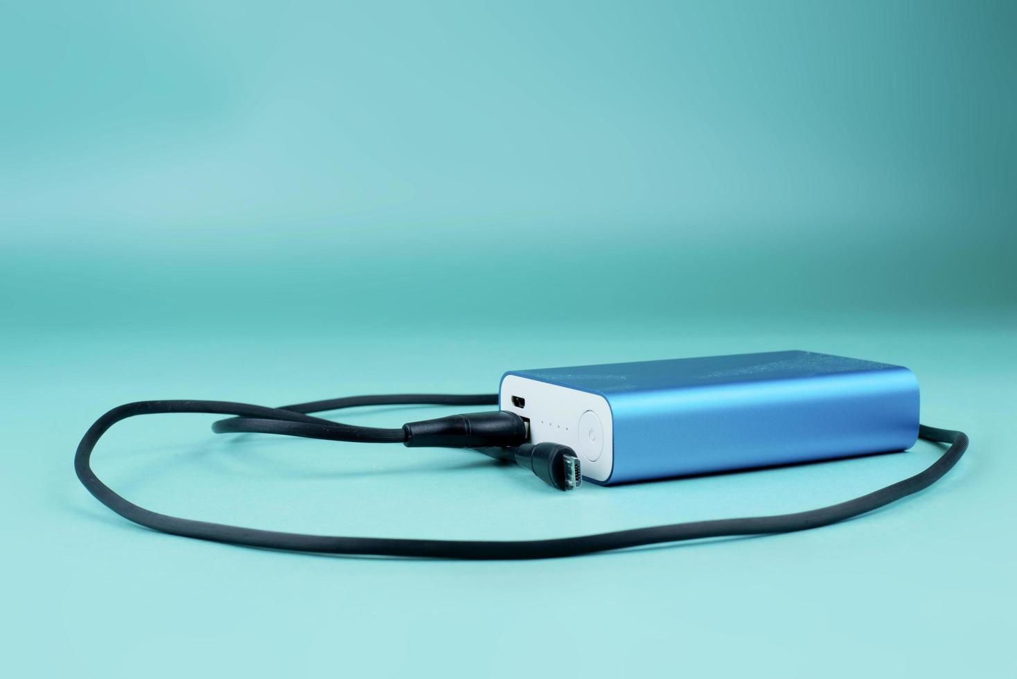 blue power bank with black cable on blue background photo